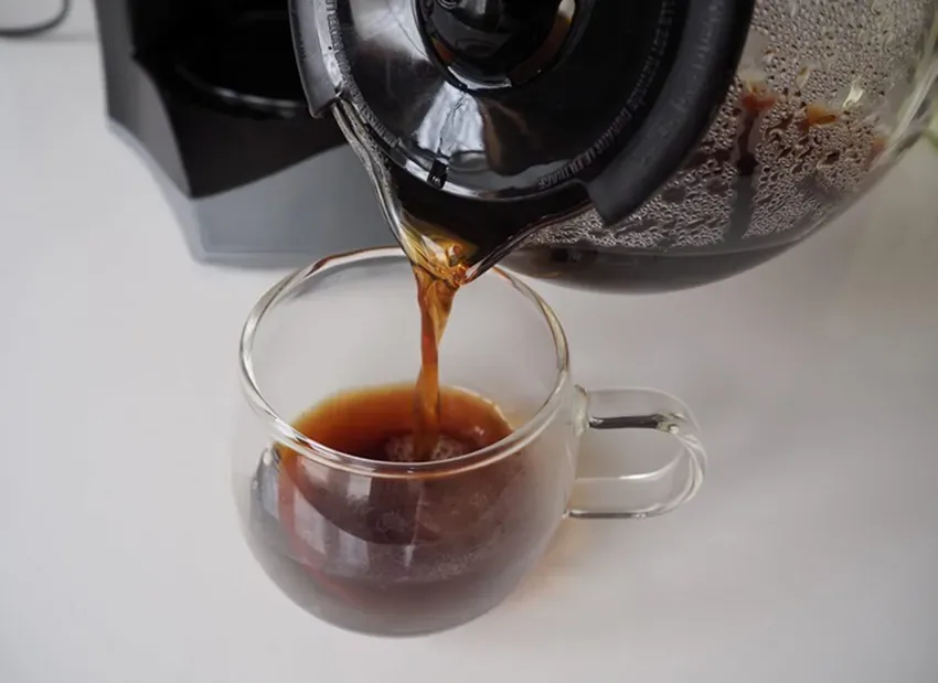 uma jarra enchendo uma xícara de café
