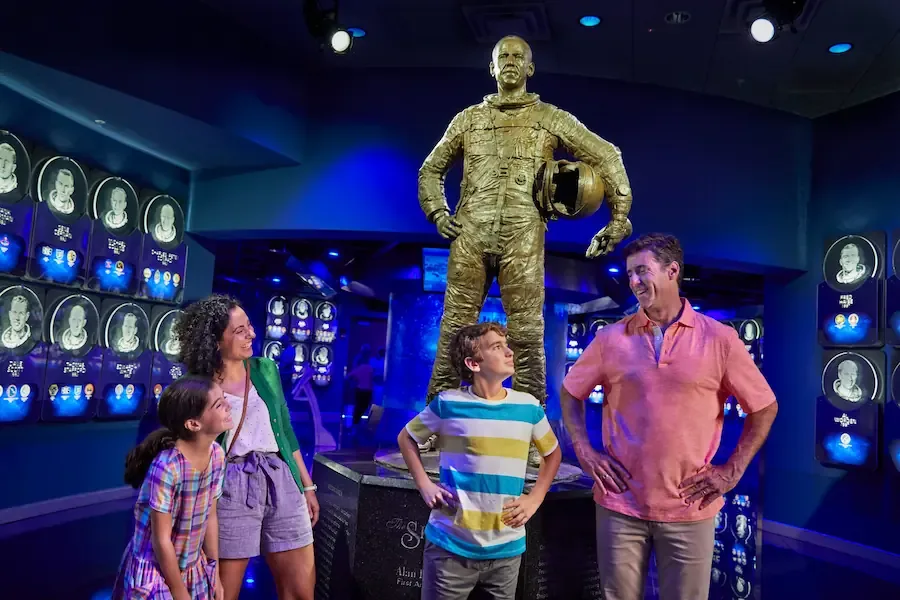 Família posa para foto em frente a estátua de astronauta durante visita ao Kennedy Space Center