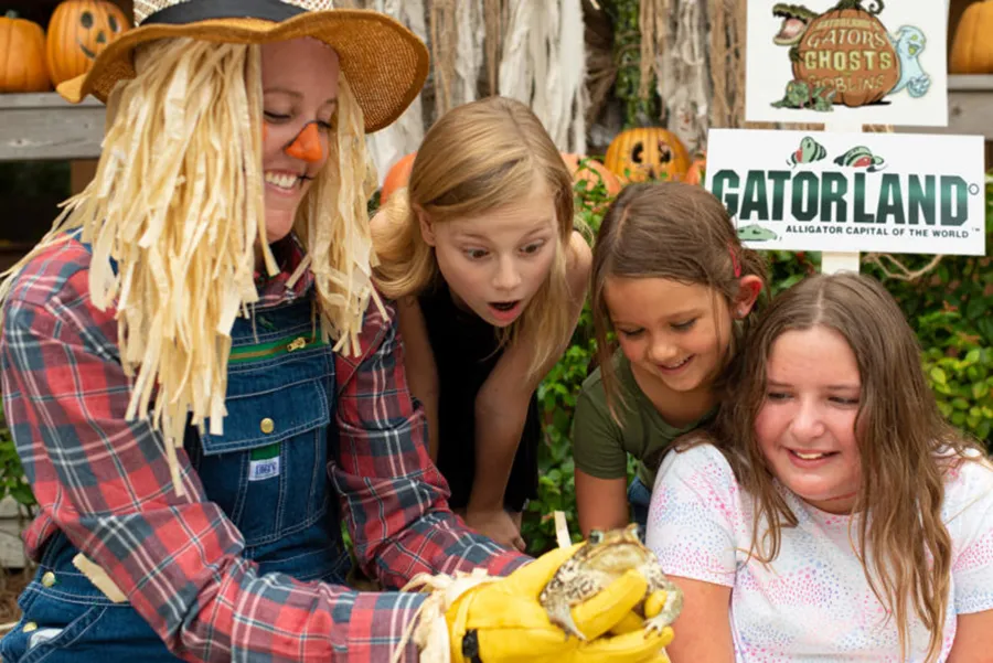Niños observan una rana en manos de un espantajo en el evento de halloween del Gatorland de Orlando