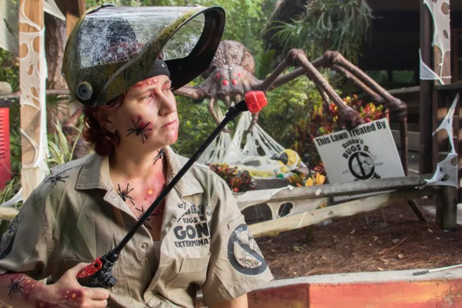Persona con uniforme de caza-insetos y máscara repleta de arañas busca por insectos gigantes en Gatorland