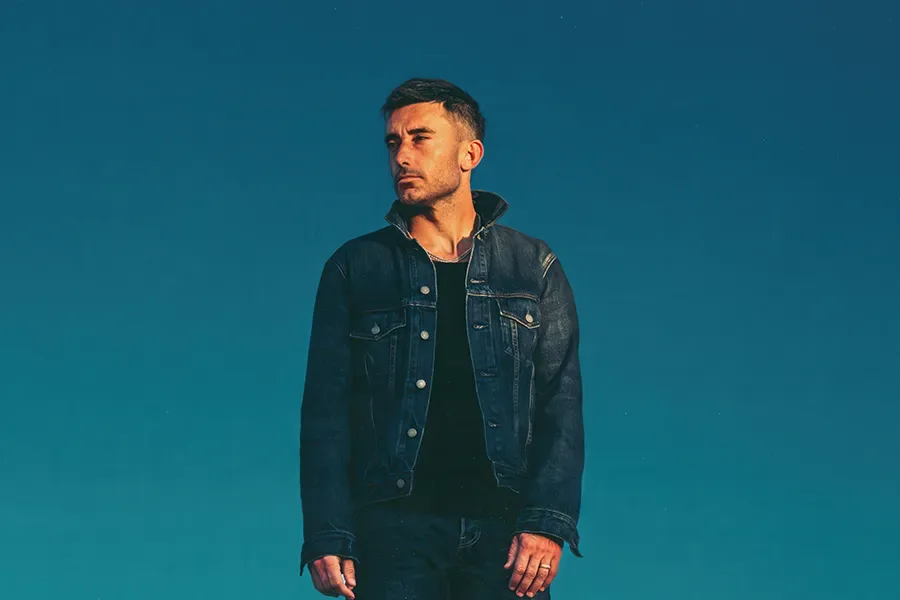 Cantor cristão Phil Wickham de perfil com um fundo azul 