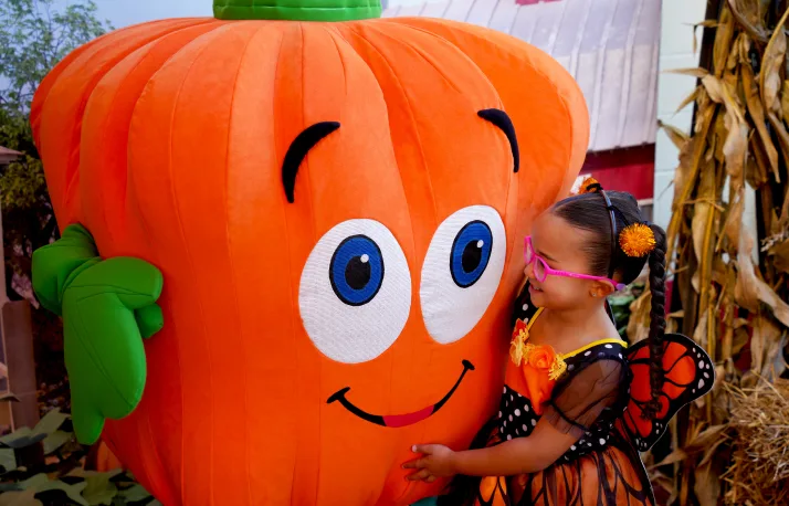 Criança abraça a abóbora quadrada do halloween do SeaWorld Orlando