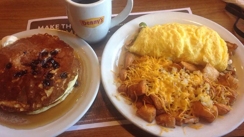 Pratos de café da manhã do Denny's, em Orlando, com panquecas banhadas com mapple, além de ovos mexidos com batatas e bacon