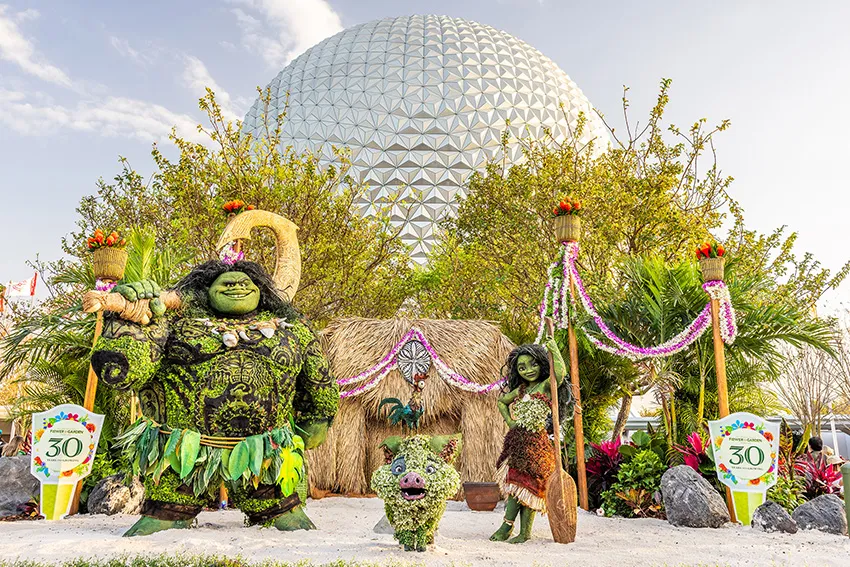 Personajes de la película Moana en forma de topiarios con la bola del Epcot al fondo