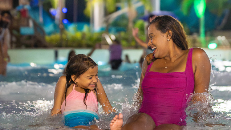 Wife and daughter sitting in a pool at night