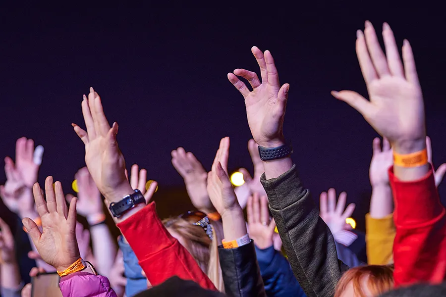 Young men with hands up in worship during a night show