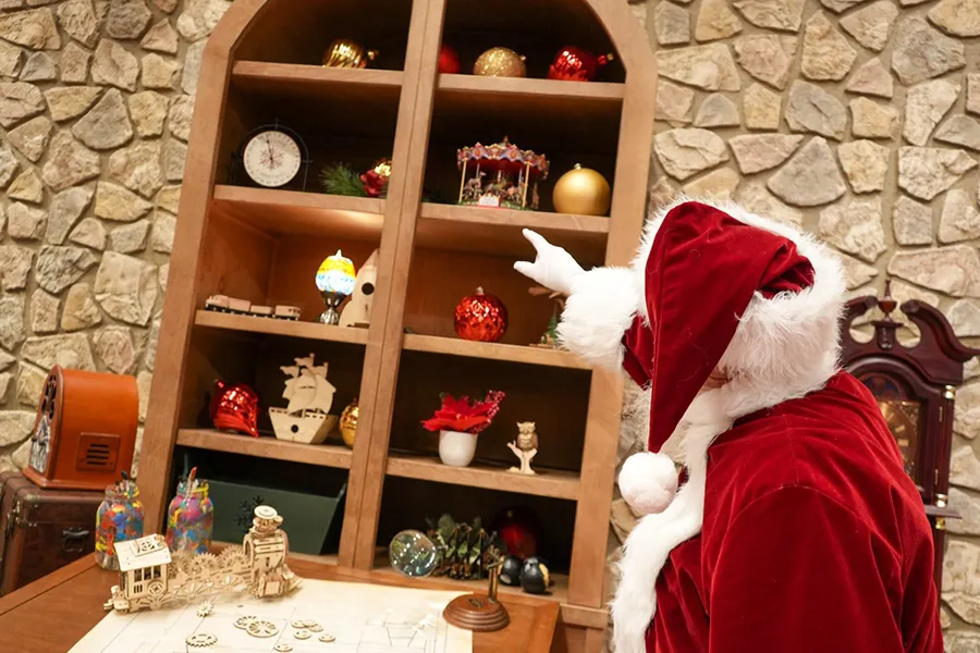 Papá Noel apunta a un estante con artículos de Navidad en Disney