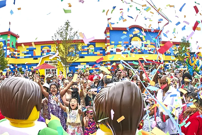 Crianças e adultos se divertem com personagens da Lego em frente a Legoland Florida