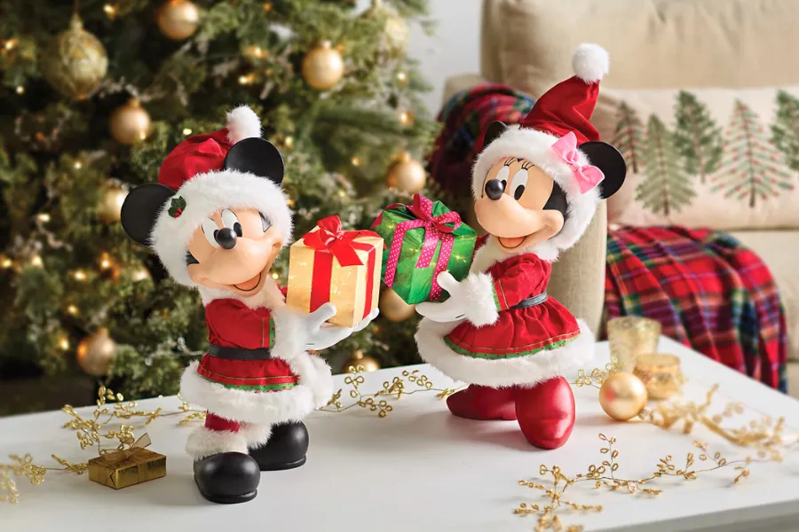 Mickey e Minnie com trajes natalinos trocando presentes em frente a uma árvore de Natal